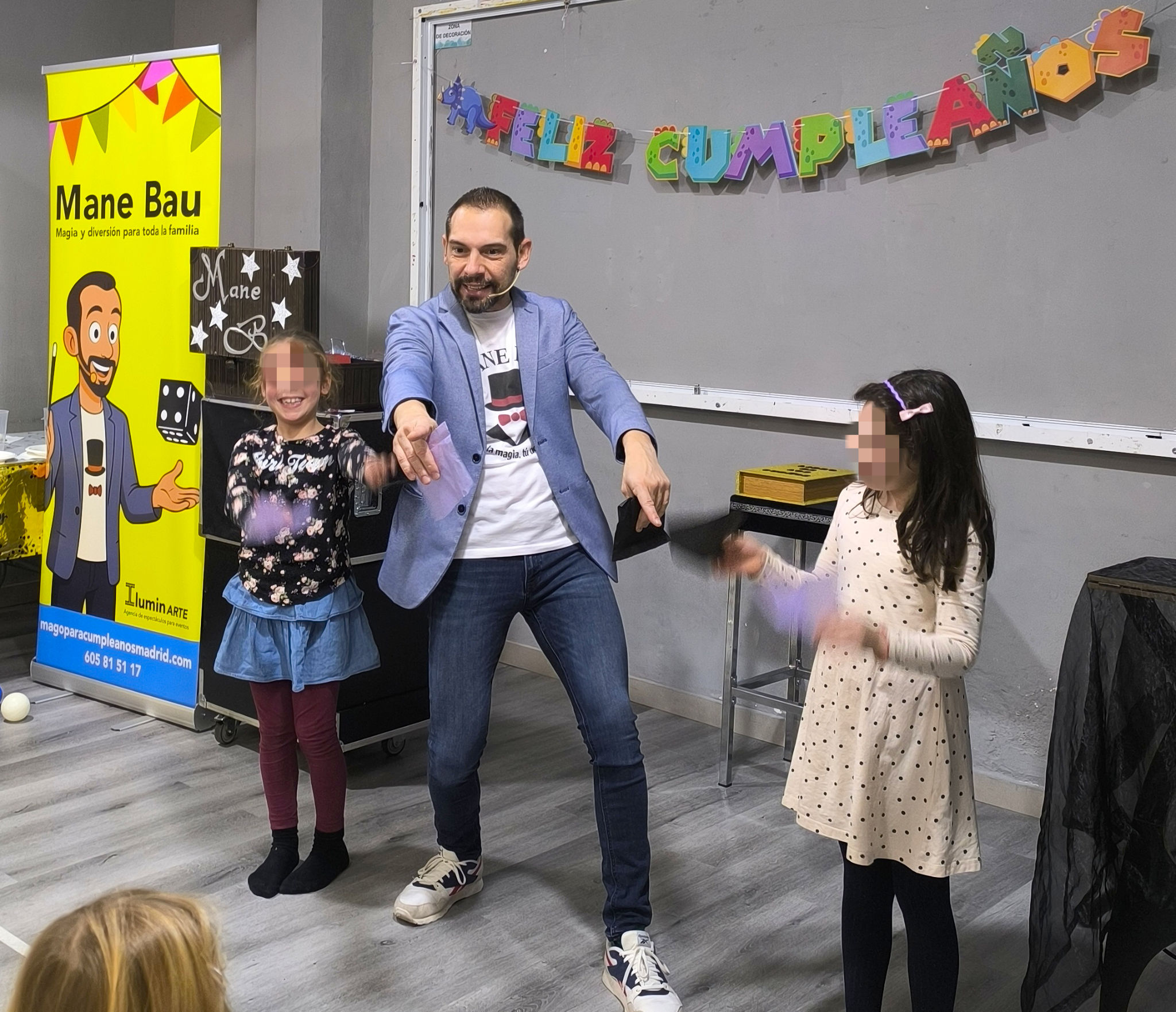 Mago Mane Bau con otras dos niñas en el escenario haciendo un juego de magia